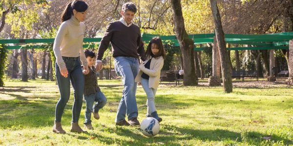 A family plays soccer together in a sunny park, enjoying quality time outdoors.