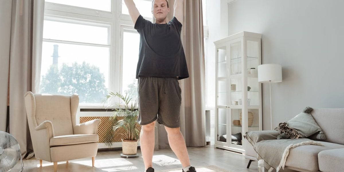 A young man enjoying a morning stretch in a bright, airy living room, embracing a healthy lifestyle.