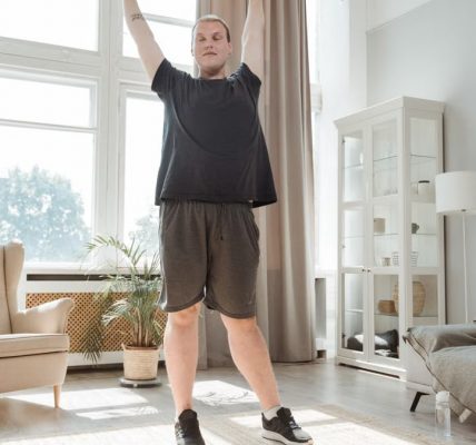 A young man enjoying a morning stretch in a bright, airy living room, embracing a healthy lifestyle.