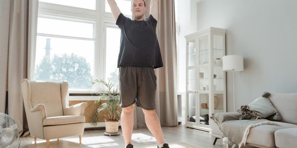 A young man enjoying a morning stretch in a bright, airy living room, embracing a healthy lifestyle.